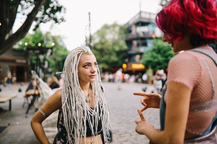 Two young women standing and talking about their friendship