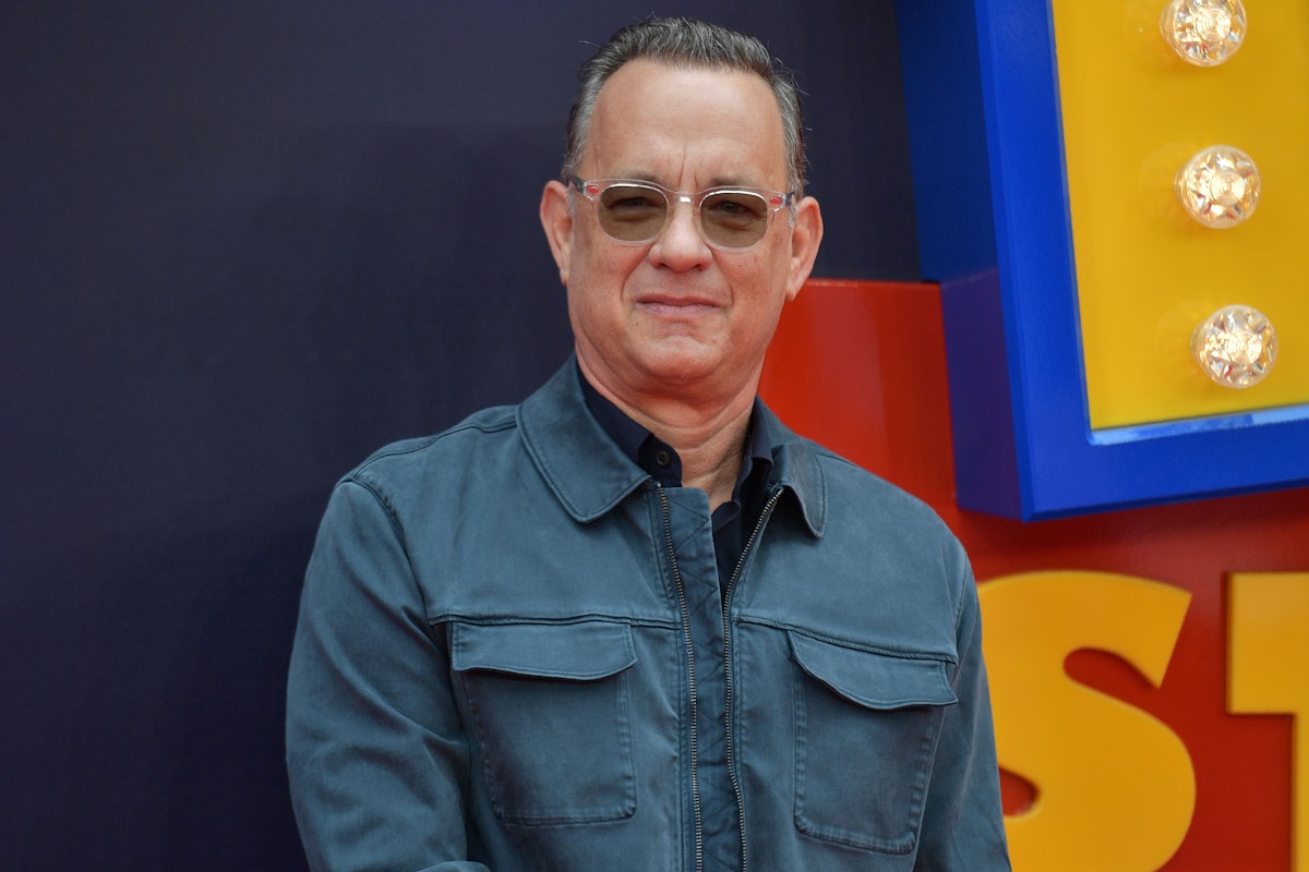 American actor Tom Hanks in a dark blue collared shirt and, blue collared jacket and sunglasses 