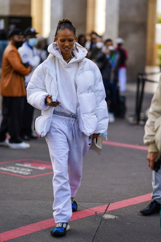 PARIS, FRANCE - OCTOBER 01: A guest wears earrings, a white hooded sweatshirt, a white puffer jacket...