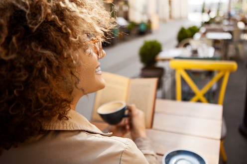 A woman drinks a cup of coffee outside; the caffeine makes her feel better.