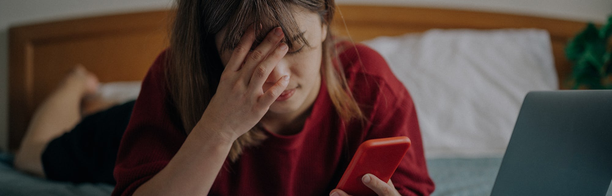 Tired overworked freelancer working with a smartphone and laptop in bed at bedroom.