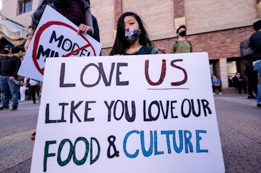 A girl wearing a face mask and holding a sign takes part in a rally "Love Our Communities: Build Col...