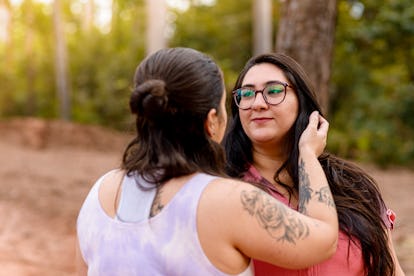 Passionate women couple hugging in woods.