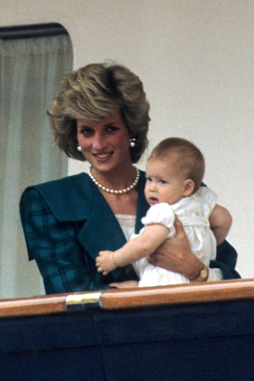 Diana, Princess of Wales, wearing a green coat designed by David and Elizabeth Emanuel, holds her so...