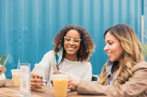 Two people smile and share iced coffee at an outdoor cafe. The differences between iced coffee and h...
