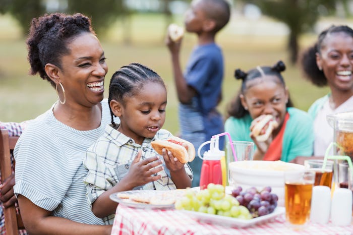Two African-American adult sisters in their 30s with their three children at a backyard cookout. The...