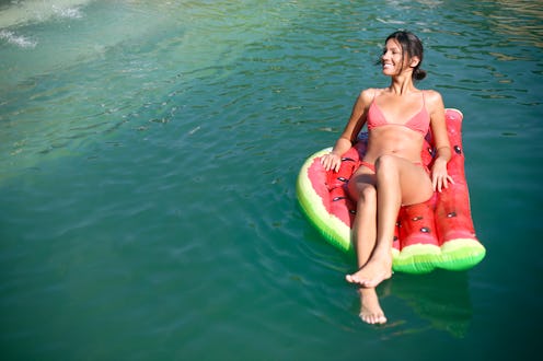 Young woman relaxing on an air mattress at a pool. About 25 years old, Caucasian brunette.