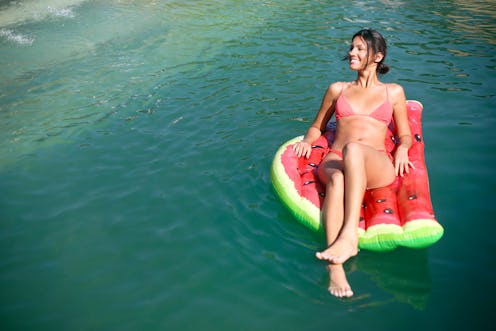 Young woman relaxing on an air mattress at a pool.  About 25 years old, Caucasian brunette.