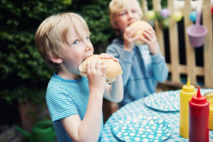 Two little boys eating burgers at a family barbecue