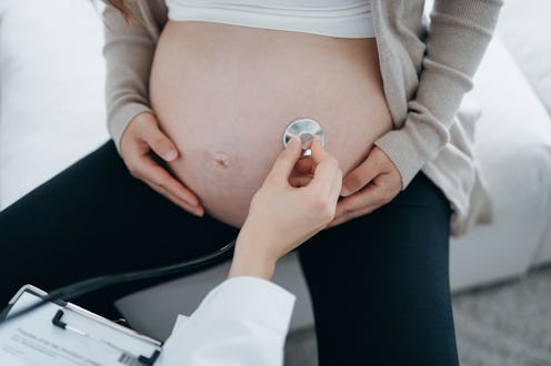 Cropped shot of pregnant woman having a consultation with doctor during routine check up at clinic. ...