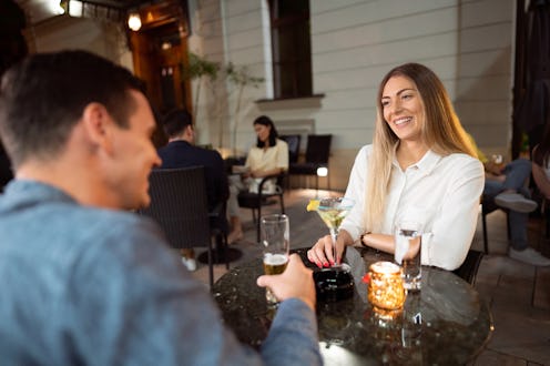Young Caucasian couple sitting in an outdoor bar at night. Young man and a young woman on a date, ta...