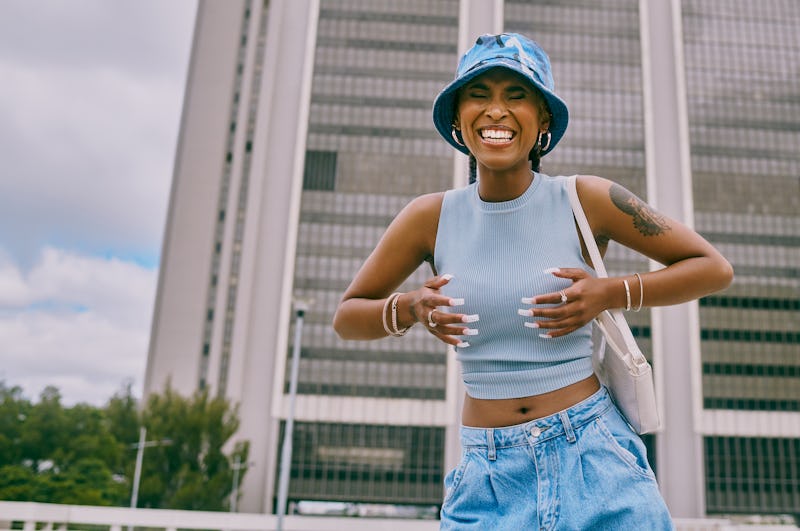 Shot of a trendy young woman covering her chest against a city background