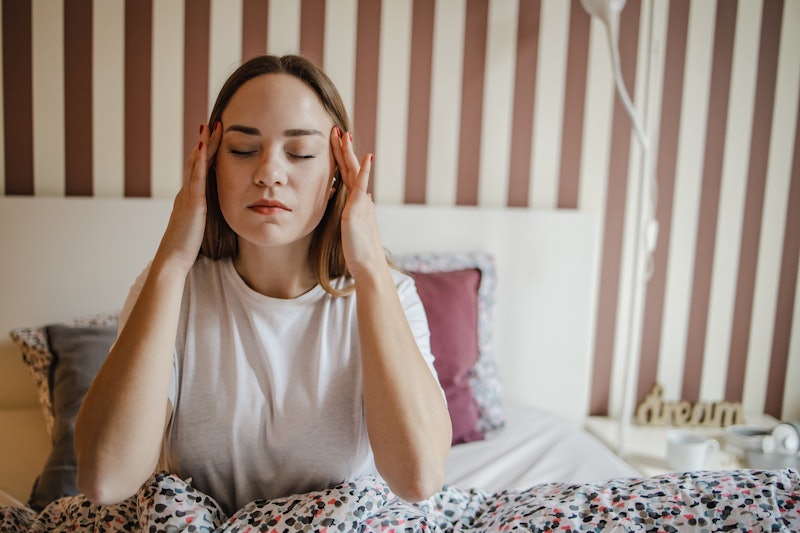 A sad young woman in bed suffers from depression and headache
