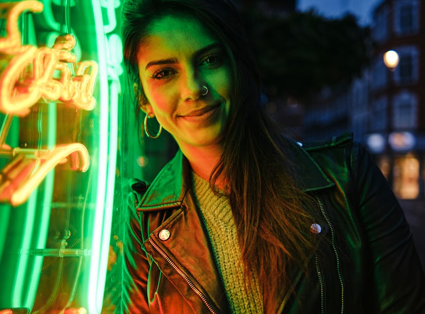 Happy young woman illuminated in green neon amid the new moon solar eclipse.