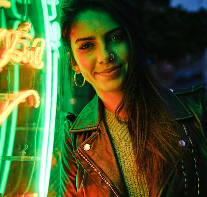 Happy young woman illuminated in green neon amid the new moon solar eclipse.