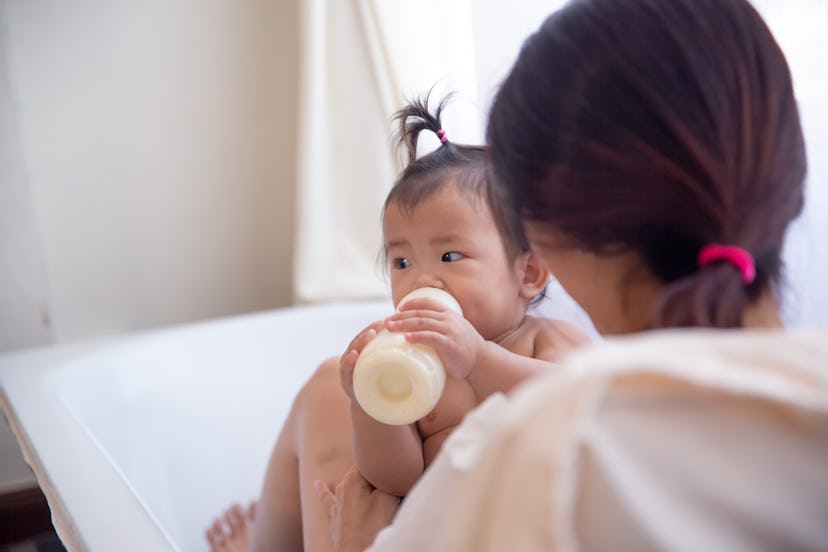 mom giving baby girl bottle