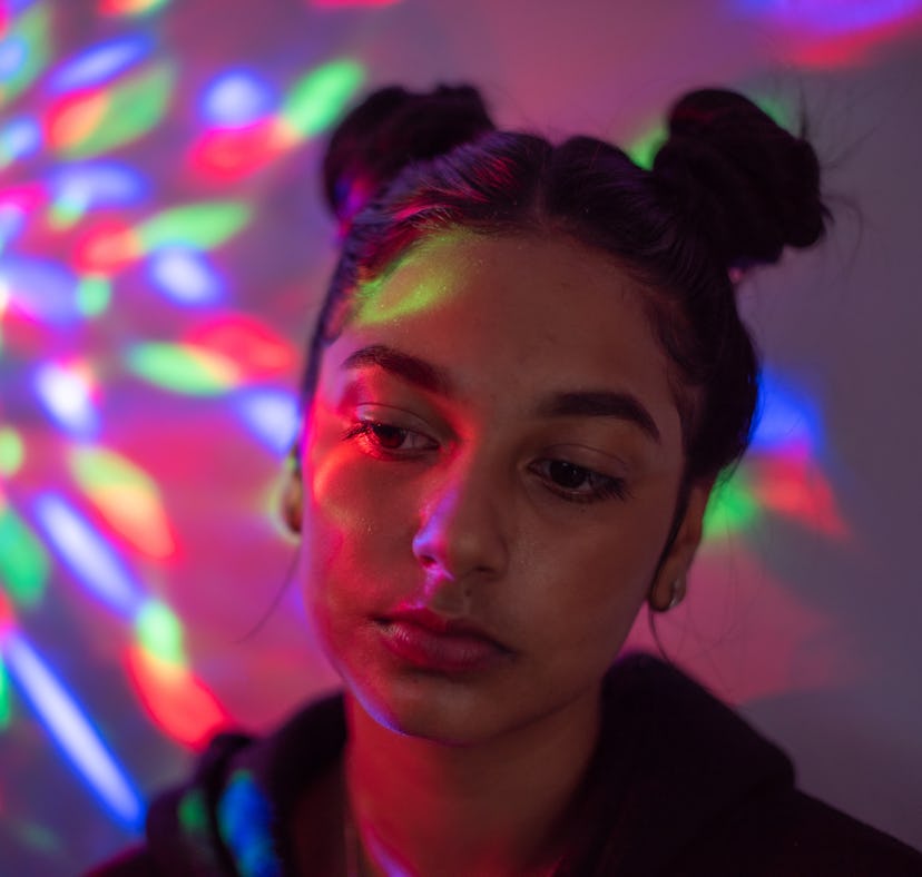 Sad young woman in neon lights amid the June 2021 new moon solar eclipse.