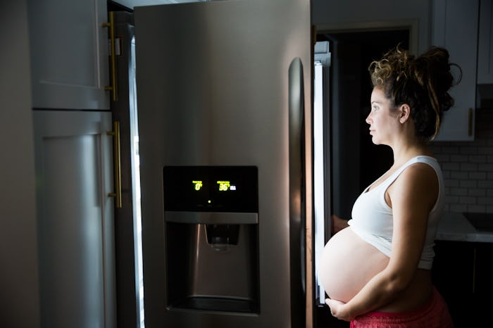 Pregnant woman in front of a fridge late at night