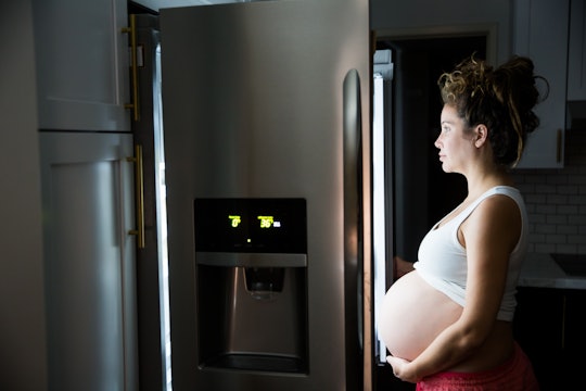 Pregnant woman in front of a fridge late at night