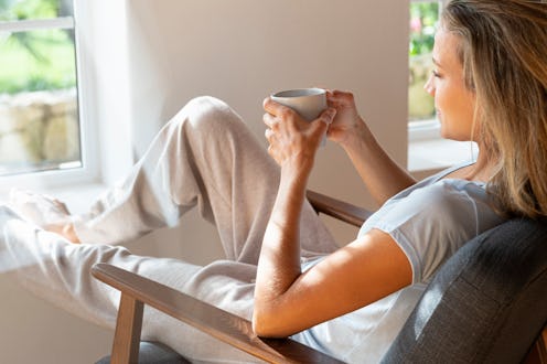 A woman drinks her coffee before getting ready for a workout. Here's how caffeine helps workouts.