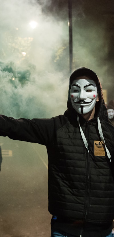 LONDON, UNITED KINGDOM - NOVEMBER 5: Demonstrator wearing Guy Fawkes mask sets of a smoke bomb as hu...