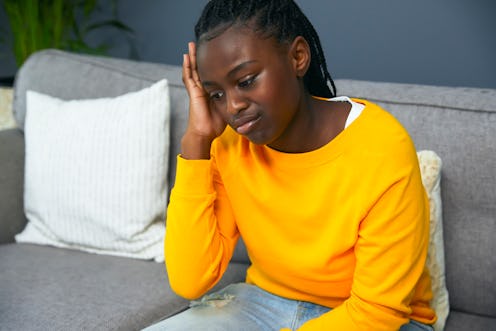 Sad teenage girls sitting on a sofa in her living room