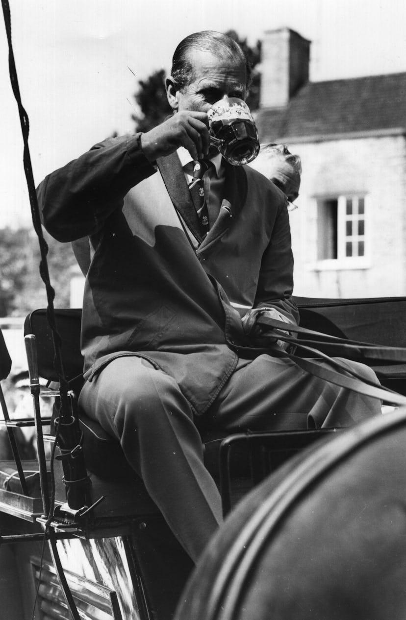Prince Philip drinks a beer while driving a carriage.
