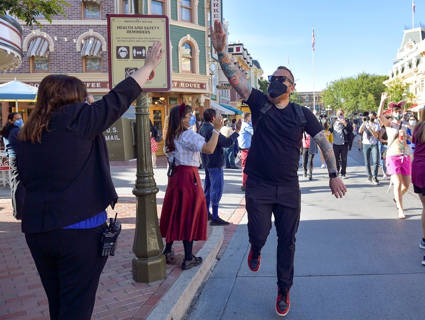 Anaheim, CA - April 30: A visitor to Disneyland high-fives employees as he walks up Main Street U.S....
