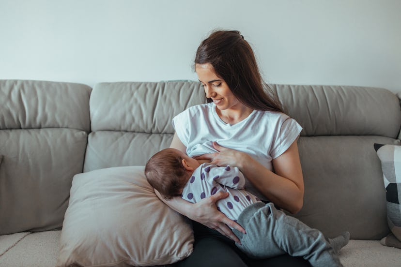 Young mother breastfeeding her baby indoors.