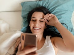 Portrait of a Happy Woman in Her Lovely Bedroom Texting. Technology, Internet, Communication and Peo...