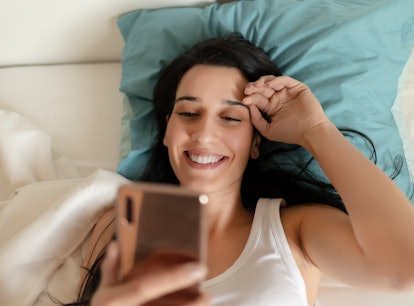 Portrait of a Happy Woman in Her Lovely Bedroom Texting. Technology, Internet, Communication and Peo...