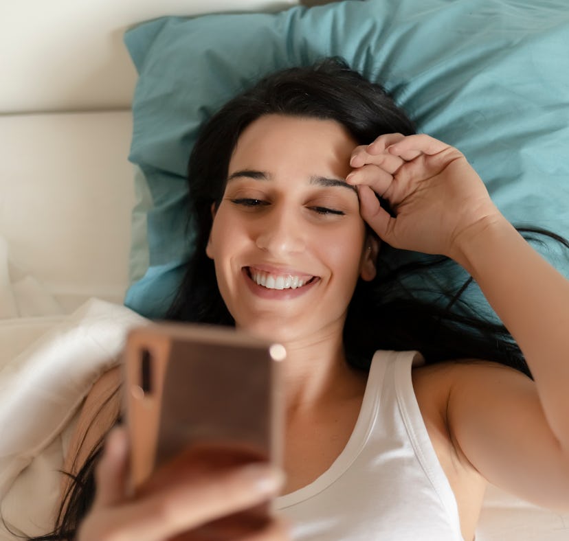 Portrait of a Happy Woman in Her Lovely Bedroom Texting. Technology, Internet, Communication and Peo...