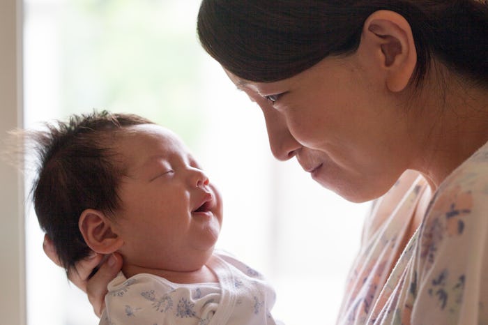 A young mother gently staring her baby on a bright window