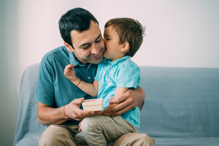 Surprised dad holding a gift and embracing his smiling child.