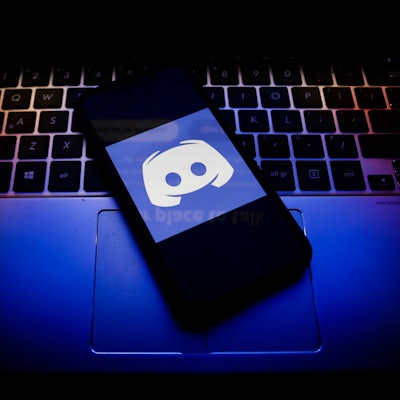 Discord logo displayed on a phone screen and a keyboard are seen in this illustration photo taken in...