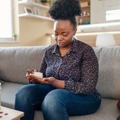 A woman sits on her couch measuring out supplements from a bottle. Experts explain the difference be...