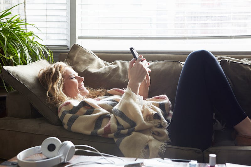 A woman on the couch turns down invitations to plans over text nicely.