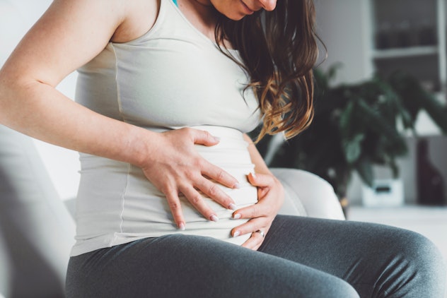 Caucasian pregnant woman suffering during her pregnancy, with back pain and headaches. Pregnant woma...