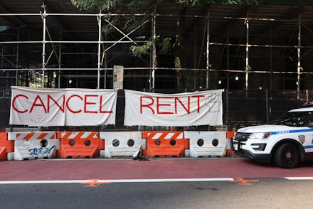 NEW YORK, NEW YORK - AUGUST 10: A NYPD vehicle parks in front of a "Cancel Rent" banner hung up by ...