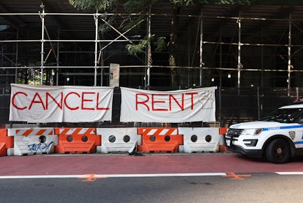 NEW YORK, NEW YORK - AUGUST 10: A NYPD vehicle parks in front  of a "Cancel Rent" banner hung up by ...