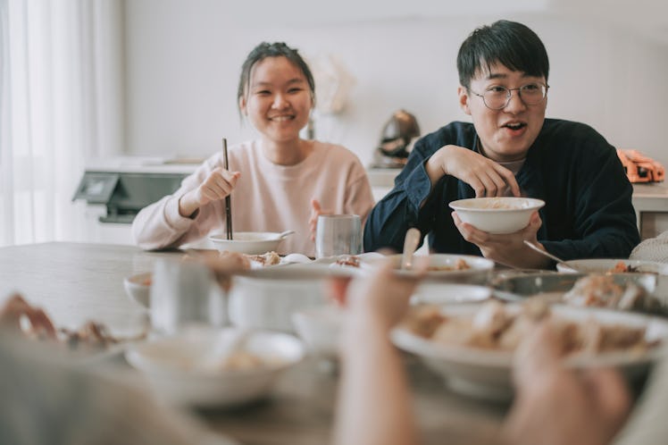 Asian chinese siblings enjoying family chinese new year reunion dinner having traditional dishes at ...