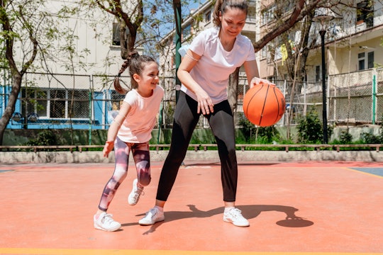 Photo of mother with her daughter playing basketball outdoors