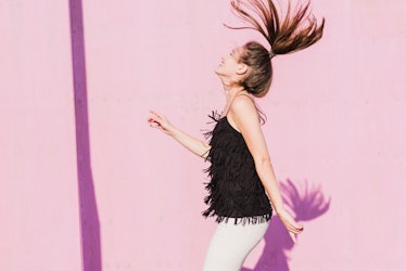 A young woman flips her hair in front of a pink wall while doing TikTok's album cover challenge.
