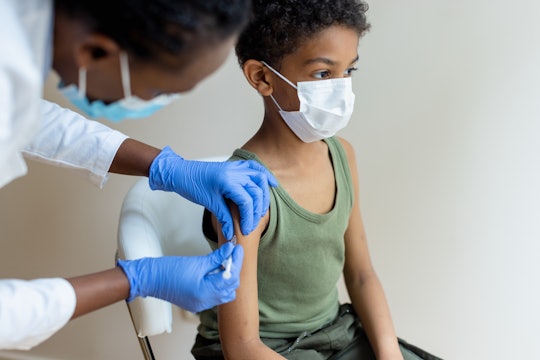 African-American, female injecting COVID-19 vaccine to a little black boy.  Shallow DOF, focus on a ...