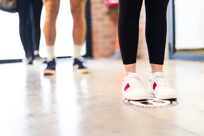 Low angle view of feet waiting in line on social distancing markers