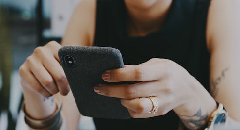 A woman looks at here phone. How To See Who Shared Your Instagram Post To Their Stories