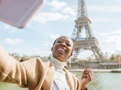 A young woman takes a vaxication selfie with the Eiffel Tower in Paris.