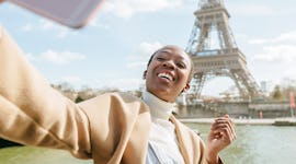 A young woman takes a vaxication selfie with the Eiffel Tower in Paris.