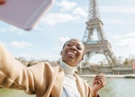 A young woman takes a vaxication selfie with the Eiffel Tower in Paris.