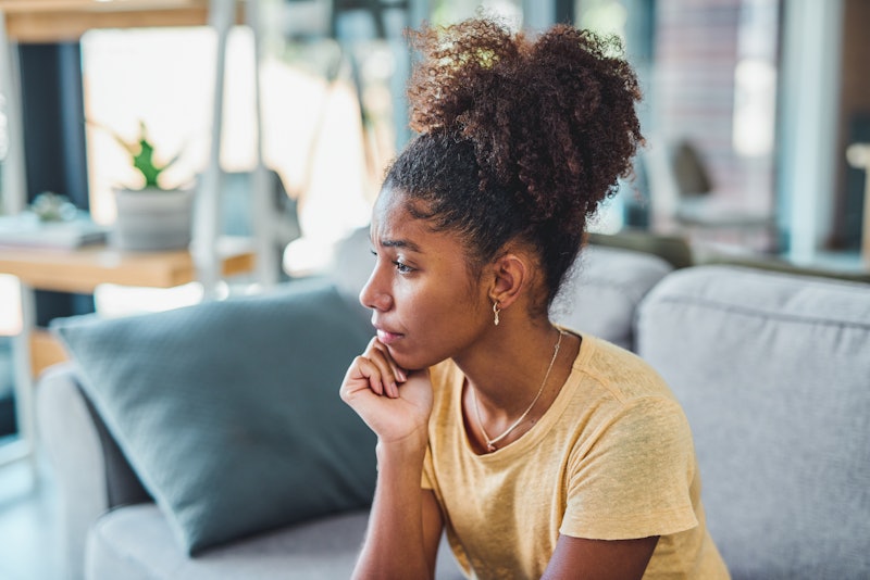 Shot of a young woman looking unhappy on the sofa at home